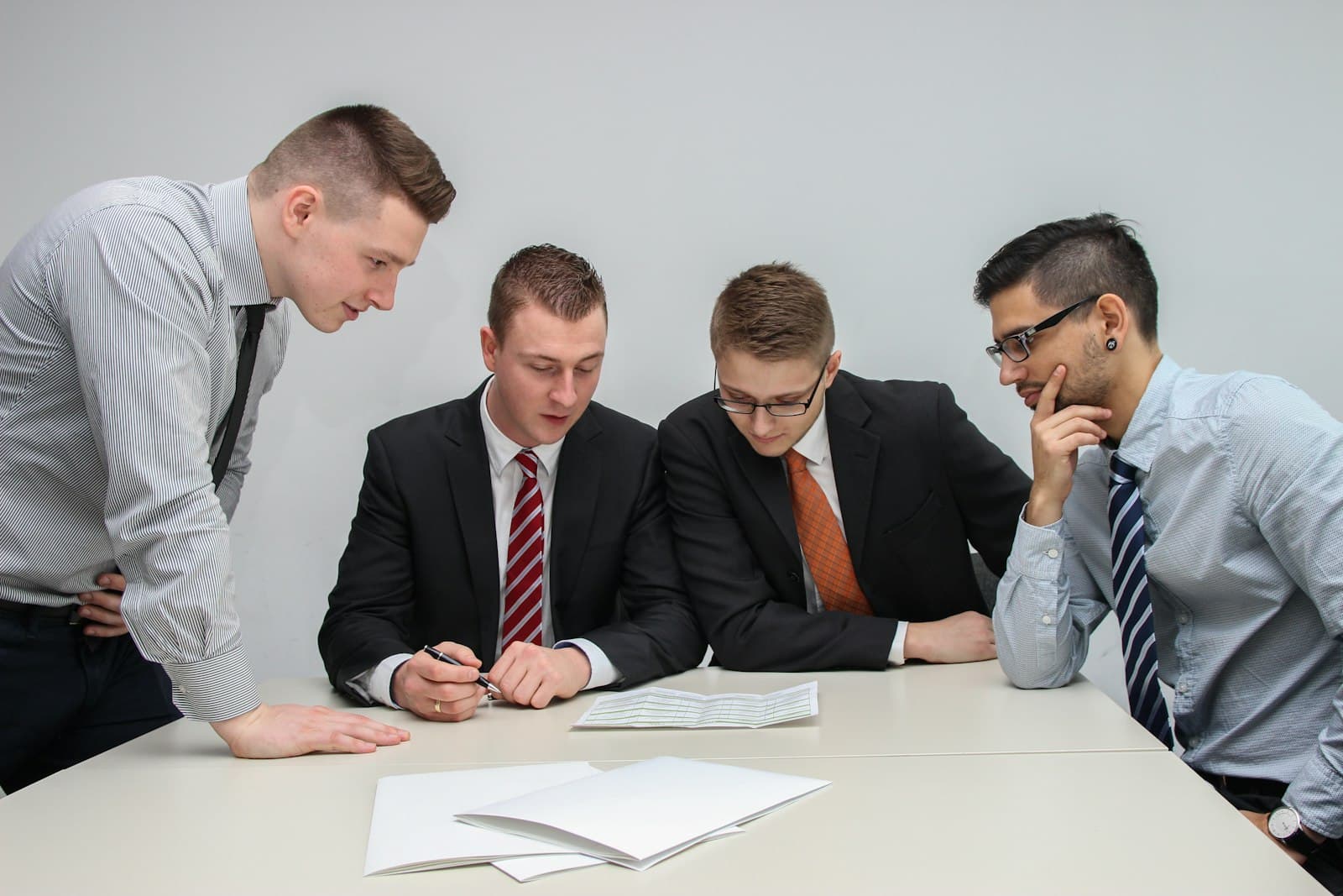 A deal team in suits reviews documents together around a table